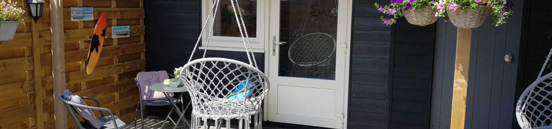 Achtertuin met schuurtje, twee stoelen en een lounge hangstoel