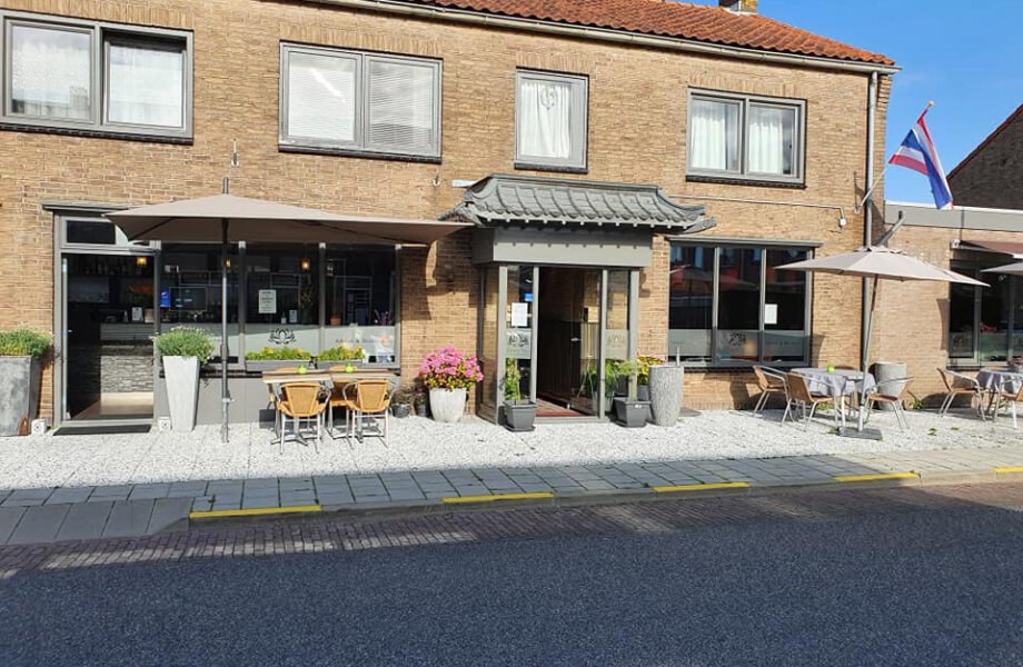 Voorgevel met terras van restaurant Thong Thai  met tafels, bloembakken en parasols