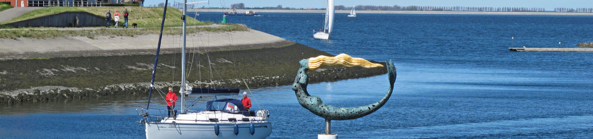Zeilboot op de Oosterscheld die naar de jachthaven Wemeldinge vaart met kunstwerk de Zeemeermin