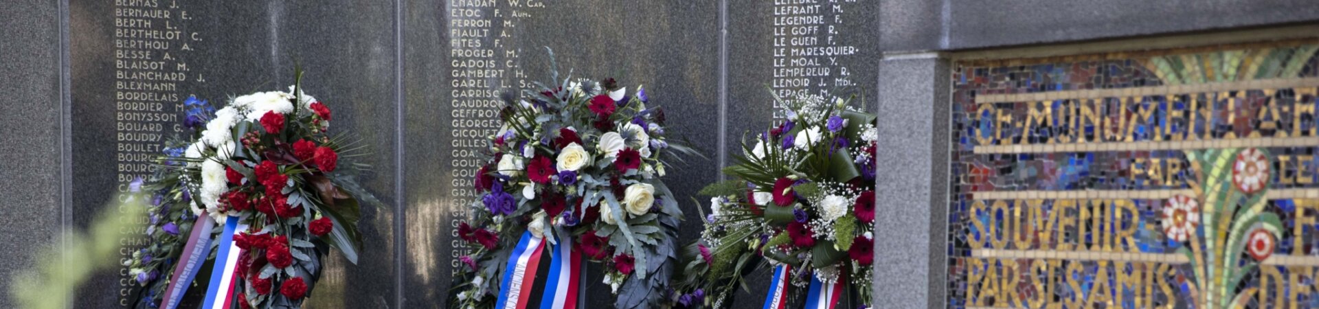 Monument Franse begraafplaats met daarvoor kransen die gelegd zijn tijdens de Franse Herdenking