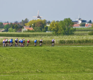 Groep wielrenners net buiten Wemeldinge met op de achtergrond de twee molens in Wemeldinge