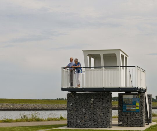 Man en vrouw kijken over de Oosterschelde vanaf het uitzichts- en informatiepunt 't Schip aan Nationaal Park Oosterschelde
